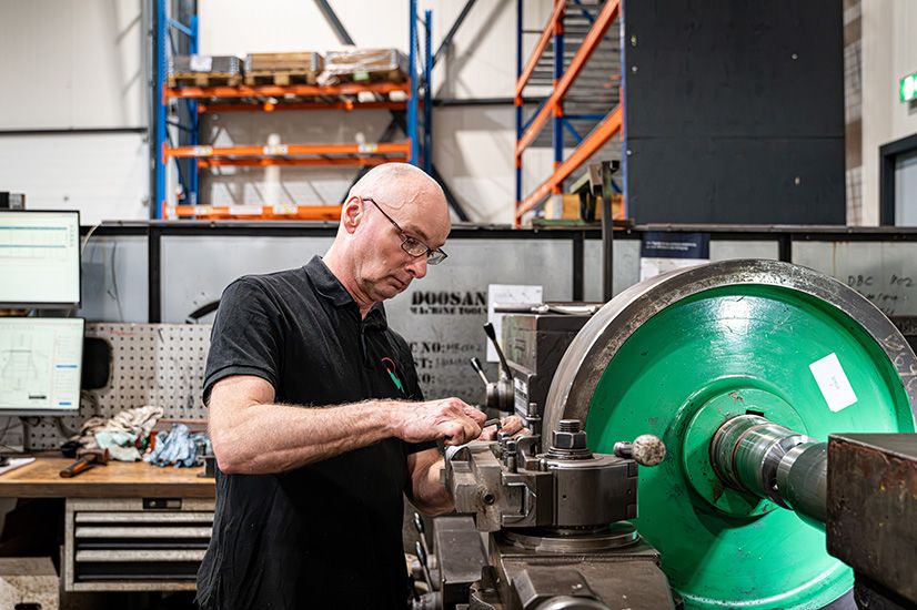 Vakman van Microtechniek bewerkt groot metalen onderdeel op draaibank voor precisietechniek, verspaning en machinebouw